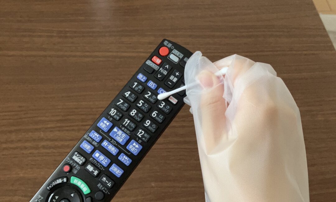 綿棒でリモコンのボタン周辺を掃除する様子